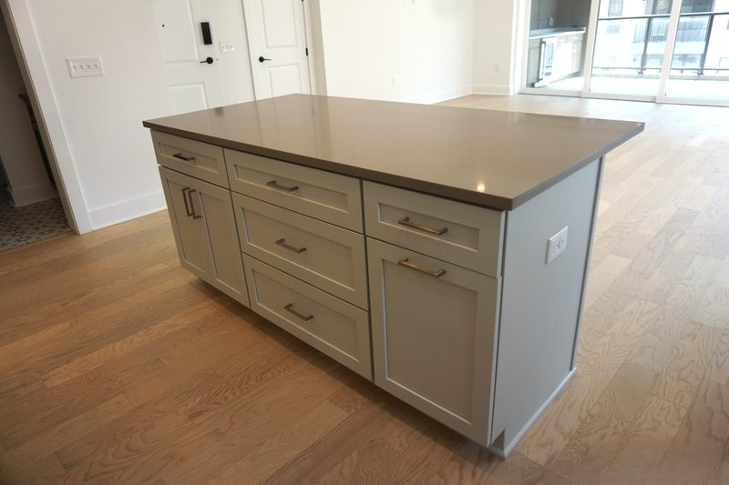 A gray painted kitchen island with Shaker doors and drawer fronts